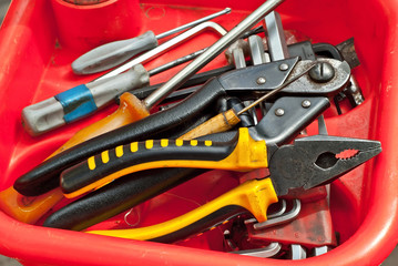 Pliers, screwdrivers and other tools for repair on a red stand. Bicycle repair equipment close up.