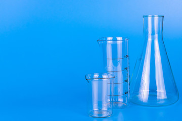 Medical laboratory glassware on blue background. Copy space.