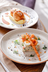 Traditional Russian salad Olivier. Salad is decorated with salmon and quail egg. Against the background of a wooden served table