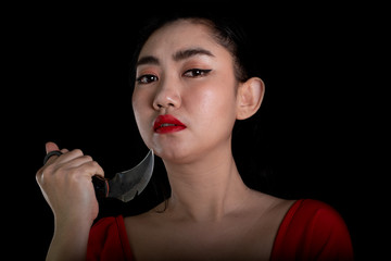 Portrait beautiful Asia woman wearing a rad dress one hand holding Karambit knife at the black...