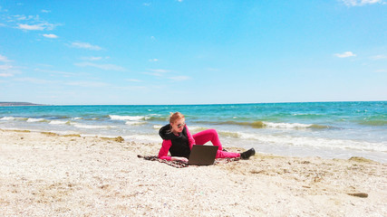 Fototapeta na wymiar Girl on the seashore with a laptop. Rest, happiness, nature, distant work.