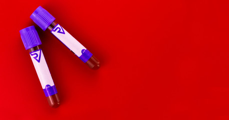 
Two laboratory test tubes with a blood test on a bright red background. Copy space.