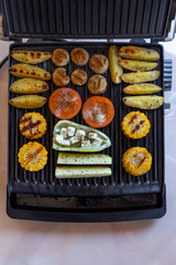 Electric grill with spicy potatoes, mushrooms and vegetables