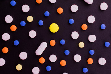 
Background from multi-colored pills. Tablets on a black background. Flat lay.