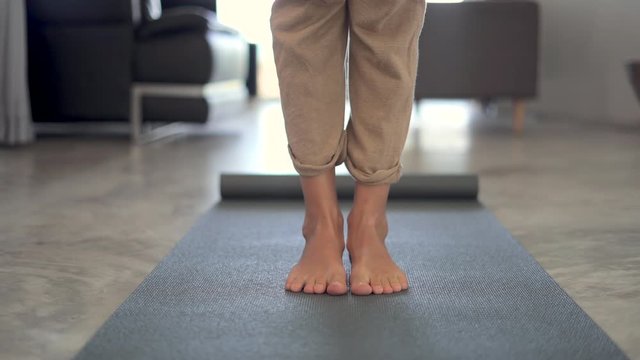 Girl rolls yoga mat and start to stretch feets