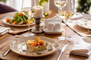 Served table with dishes. On the table are shrimp salad, olivier salad, mashed potatoes with meatballs and an English breakfast. White wine is served for the meal.