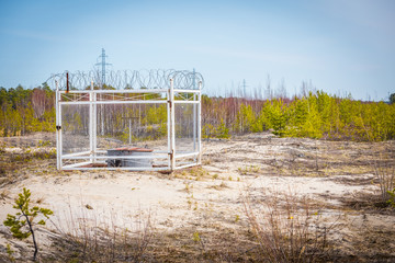 Fenced oil compressor with an iron fence and barbed wire mounted on the sand outside the city in flattering area.