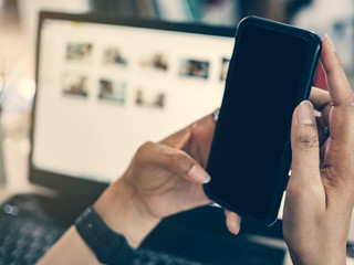 Hand holder smartphone blank screen with desk background