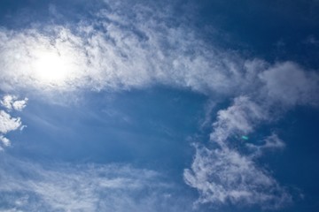 Naklejka na ściany i meble White clouds on the blue clean sky with sun rays. 