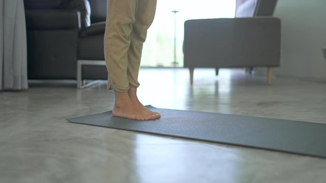Woman rolling out yoga mat and kneads the feet Girl preparing for exercises