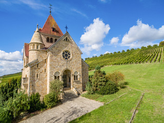 Fototapeta na wymiar Kreuzkapelle in Gau-Bickelheim am Wissberg in Rheinhessen. Die Kreuzkapelle oberhalb des rheinhessischen Gau-Bickelheim steht so malerisch auf dem Wißberg, umgeben von einem Meer aus Reben.