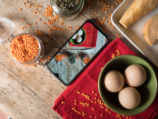 Orange lentils eggs, sunflowers seeds and other vegetables with a smartphone picture.