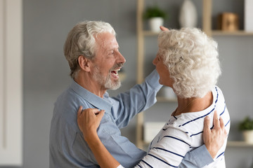 Happy loving married middle aged couple dancing in pair to favorite slow music at home, side view head shot. Smiling emotional family spouses having fun, enjoying romantic weekend activity together.