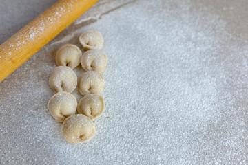 Homemade dumplings close-up.  Dumplings ears lie on a table sprinkled with flour