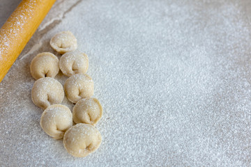 Homemade dumplings close-up.  Dumplings ears lie on a table sprinkled with flour