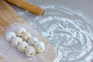 Fototapeta na wymiar Homemade dumplings close-up. Dumplings ears lie on a table sprinkled with flour