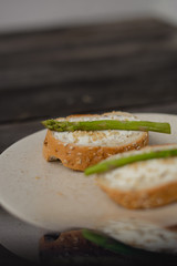 sandwich with asparagus curd cheese on a ceramic light plate on a wooden background