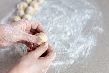 Woman sculpts homemade dumplings bear ears in the kitchen.  Modeling dumplings closeup.  Female hands sculpt dumplings.