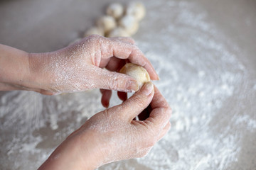 Woman sculpts homemade dumplings bear ears in the kitchen.  Modeling dumplings closeup.  Female hands sculpt dumplings.