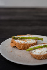 sandwich with asparagus curd cheese on a ceramic plate on a wooden background