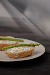 sandwich with asparagus curd cheese on a ceramic light plate on a wooden background