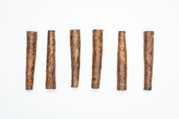Small cigars lie in row on white background.