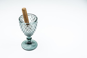 Cuban cigars from twisted sheets in glass beaker with white background.