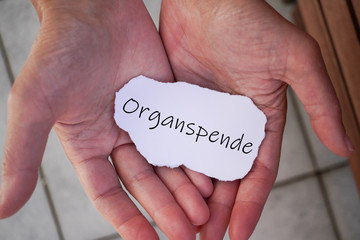 Hände mit einem Zettel auf dem Organspende steht