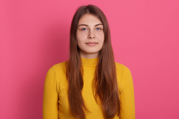 Fototapeta premium Picture of serious or calm female with pleasant appearance, looking at camera, wearing casual attire, posing isolated over pink studio background. Studio shot of attractive lady posing indoors.