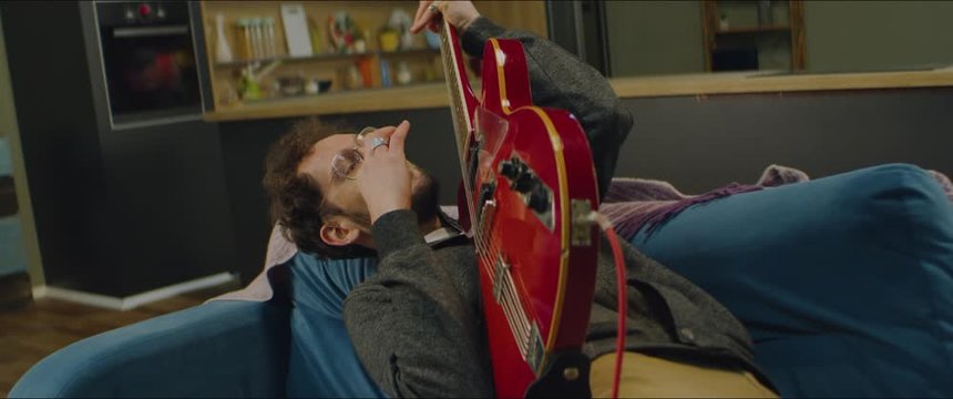 DX MED aucasian male going crazy while playing his electric guitar at home, practicing during quarantine. Shot on RED Helium in 8K with Atlas Orion 2x Anamorphic lens