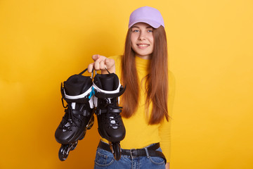 Pretty attractive woman dresses casually, looking directly at camera, showing her rolling skates,...