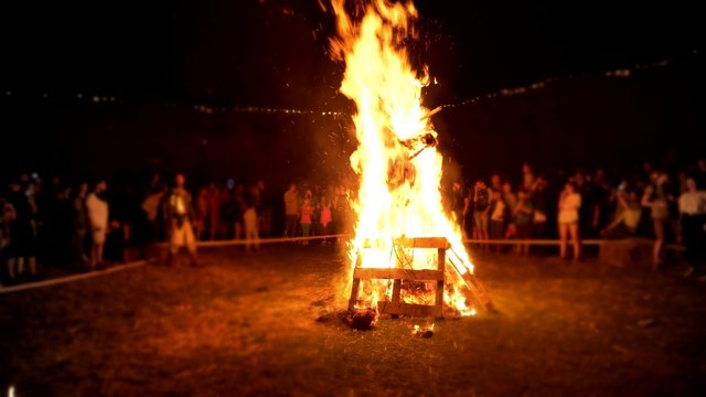Silhouettes of people around big ritual bonfire.