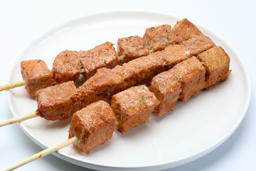 Pincho o brocheta de carne asada en un plato con fondo blanco
