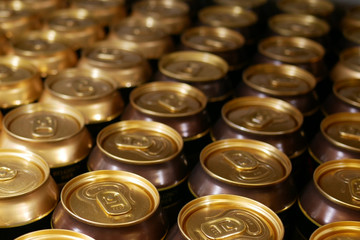 Many aluminum cans stand in a row on a shelf close-up. Tops of aluminum cans closeup in a row on a rack.