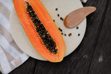 cutaway papaya on a white plate on a linen tablecloth and wooden table