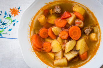 Traditional homemade Hungarian hot goulash soup with mear, potato, carrot and mushrooms in a white...