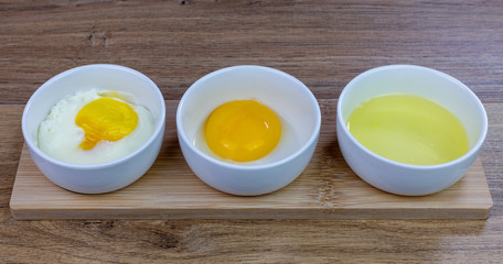 aligned white ceramic bowls containing: a cooked egg, yolk and egg white