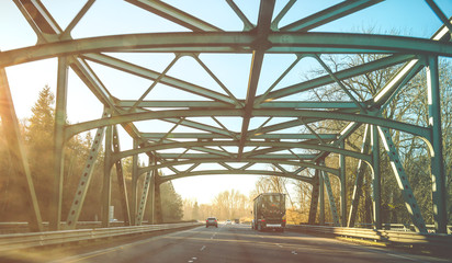 scene of a big truck drive on the road with  steel bridge structure when sunset.