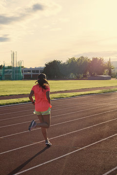 Teenage Girl Running Backwards On The Track Towards Sunset