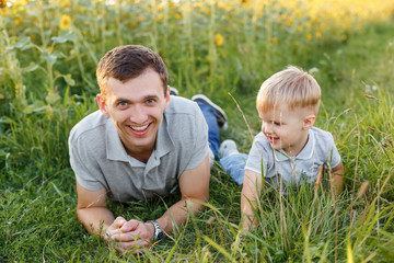 Father and son having fun on the grass. Little boy and his dad lying and laughing. Summer outdoors lifestyle, family leisure, parenthood