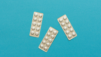 Blister packs with pills on a blue background, lowering blood cholesterol with statin tablets