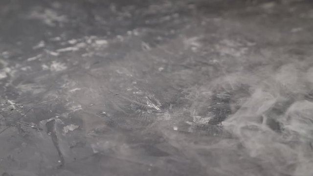 Dry ice fog flows on black concrete background. Chemical reaction with water. Side view, close up.