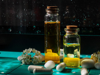 Bottle oil cosmetic in clean transparent water with sunlight on blue background. The bottle of Moisturizing cosmetic oil in the water waves on the summer flowers blur background.