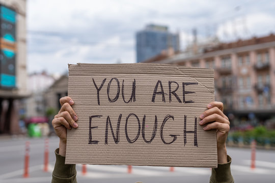 You Are Enough Support Phrase For Body Positive Movement. Self-respect And Self Love Support.  Hands Holding Banner Outside On City Streets. Social Care Motivation Concept. Friendly Mood Attitude.