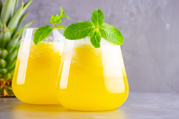 Pineapple juice on a gray background. Juice for detox in the glass. Pineapple smoothie with fresh pineapple. Healthy summer drink with mint