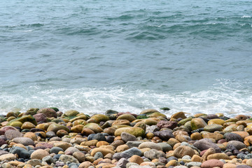 Fototapeta na wymiar A sea wave rolls onto the coastal boulders. Background. Abstract.