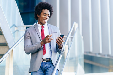 Black Businessman using a smartphone near an office building