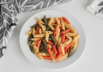 Coloured Italian wheat pasta on a white plate. Healthy food. 