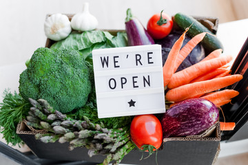 Text We're open and Fresh green and vegetables box
