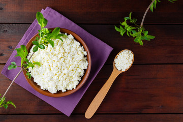Cottage cheese on wooden boards. Fresh cottage cheese in a ceramic bowl. Soft cheese and wooden spoon on a linen napkin. Top view. Copy space
